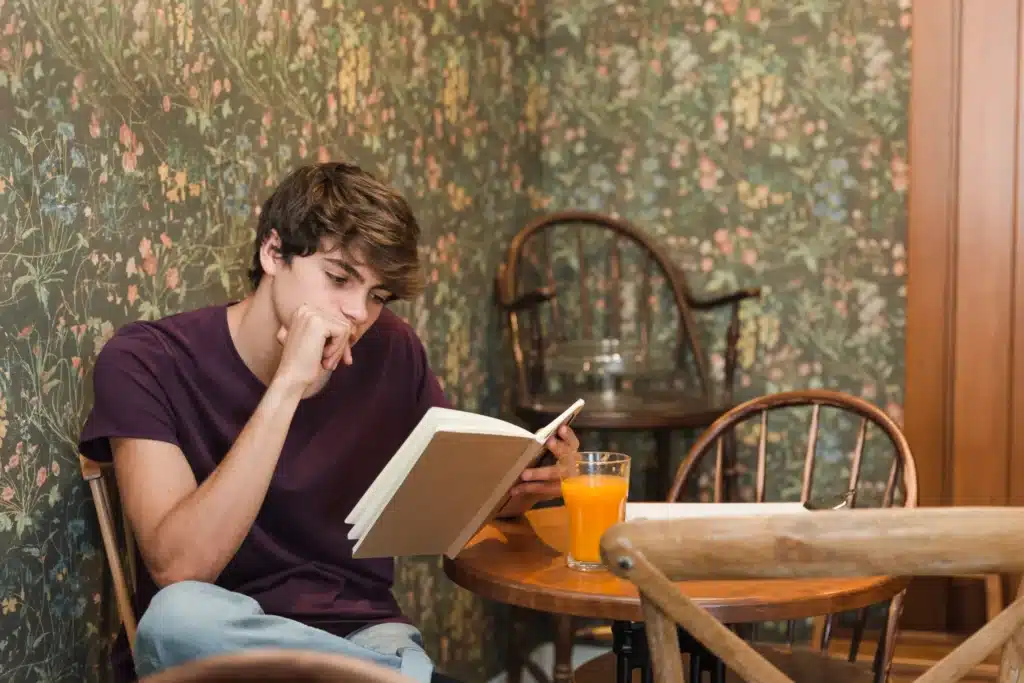 male teenager reading book thinking